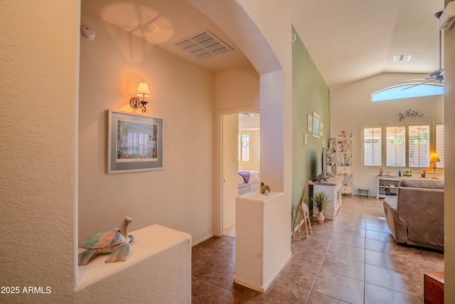 corridor featuring arched walkways, tile patterned flooring, lofted ceiling, and visible vents