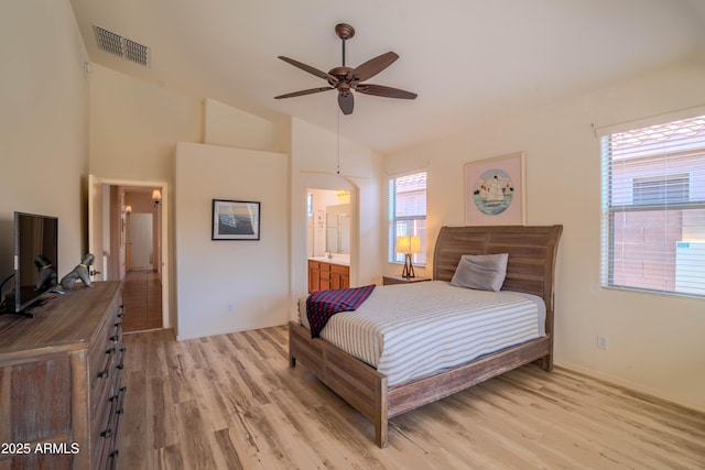 bedroom with visible vents, vaulted ceiling, light wood-style flooring, and ensuite bath