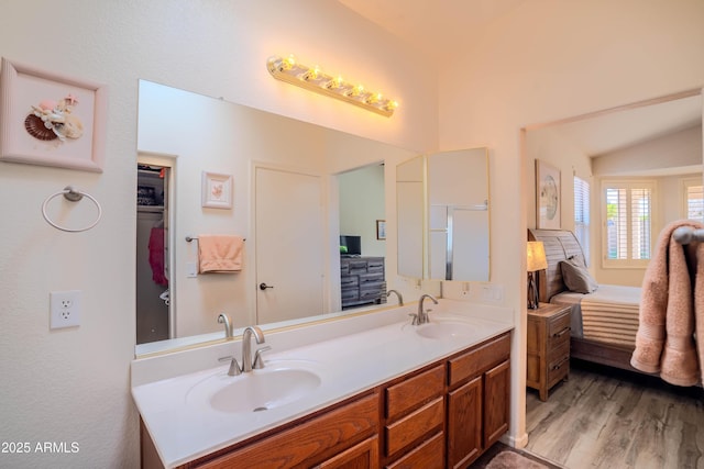 full bath with double vanity, ensuite bath, a sink, and wood finished floors