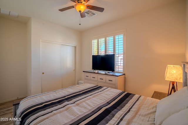 bedroom with ceiling fan, visible vents, a closet, and wood finished floors