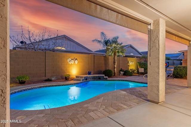 pool at dusk with a patio area, a fenced backyard, and a fenced in pool