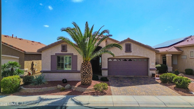 view of front of home featuring a tiled roof, decorative driveway, an attached garage, and stucco siding