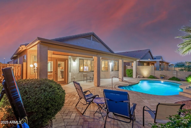 pool at dusk featuring fence private yard, a fenced in pool, and a patio