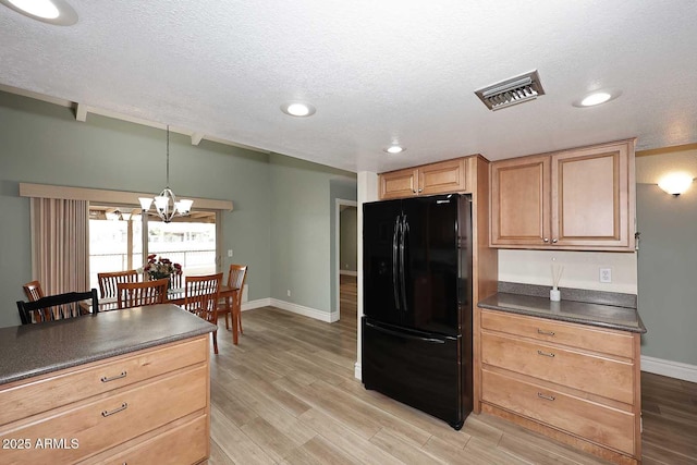 kitchen featuring decorative light fixtures, a textured ceiling, black refrigerator, a notable chandelier, and light hardwood / wood-style floors