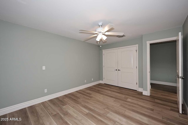 unfurnished bedroom with wood-type flooring, a closet, and ceiling fan