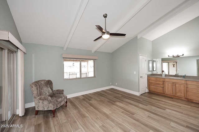 living area featuring light wood-type flooring, ceiling fan, sink, and vaulted ceiling with beams