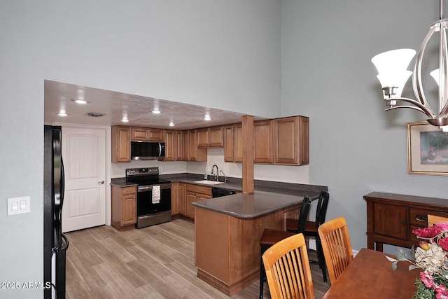 kitchen with sink, black appliances, kitchen peninsula, and light wood-type flooring