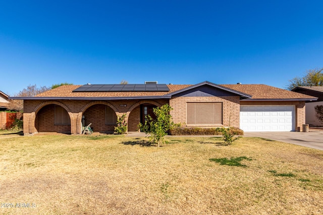 ranch-style house featuring an attached garage, covered porch, solar panels, driveway, and a front yard