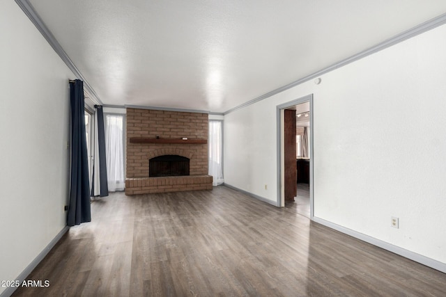 unfurnished living room with a fireplace, baseboards, crown molding, and wood finished floors