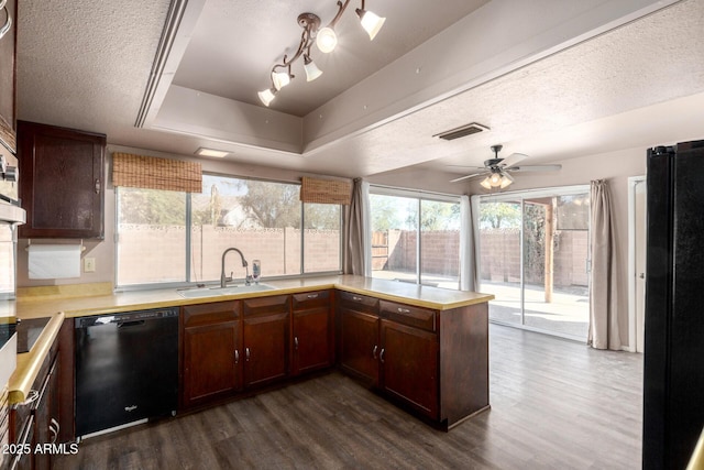 kitchen featuring dark wood finished floors, light countertops, a sink, and black appliances