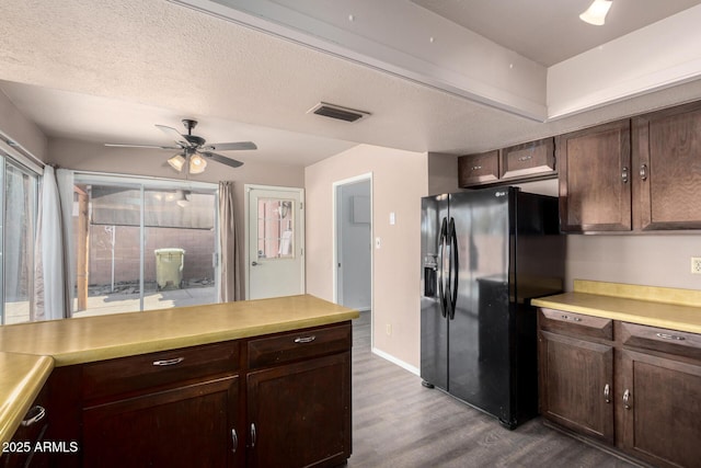 kitchen featuring dark wood-style floors, light countertops, visible vents, and black fridge with ice dispenser