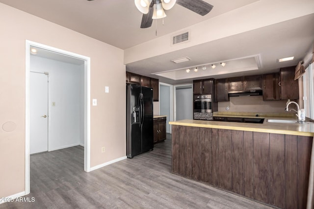 kitchen with dark brown cabinetry, a sink, visible vents, black fridge, and a tray ceiling