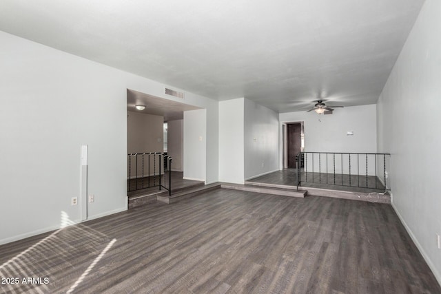 unfurnished room featuring dark wood-type flooring, visible vents, baseboards, and a ceiling fan