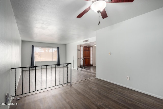 spare room featuring visible vents, a textured ceiling, baseboards, and wood finished floors