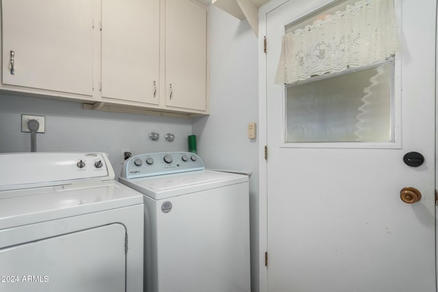 clothes washing area featuring washing machine and clothes dryer and cabinets