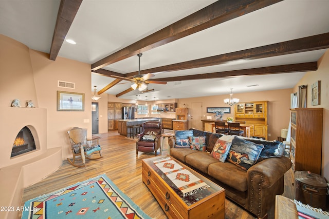 living room with beam ceiling, a large fireplace, light hardwood / wood-style floors, and ceiling fan with notable chandelier