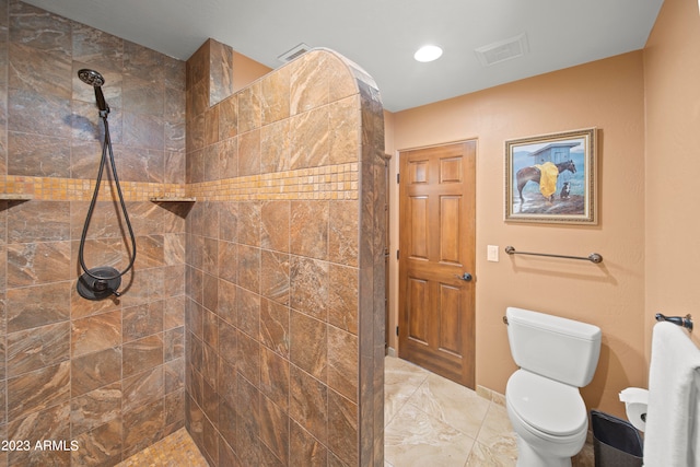 bathroom with a tile shower and toilet