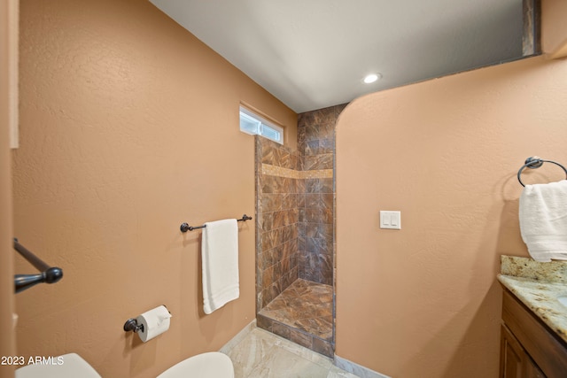 bathroom with toilet, vanity, and tiled shower