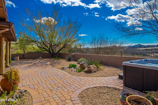 view of patio with a mountain view and a hot tub