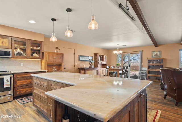 kitchen with a center island, dark wood-type flooring, an inviting chandelier, beamed ceiling, and appliances with stainless steel finishes