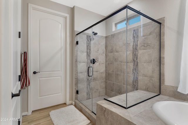 bathroom with wood-type flooring and shower with separate bathtub