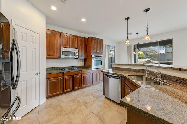 kitchen featuring dark stone counters, appliances with stainless steel finishes, hanging light fixtures, a sink, and recessed lighting