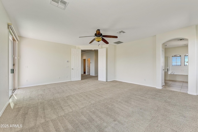 unfurnished room with light carpet, visible vents, and arched walkways