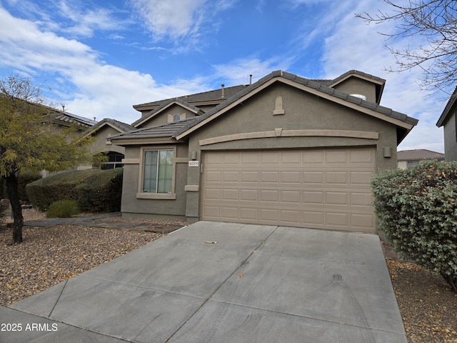 view of front of home with concrete driveway, a tile roof, an attached garage, and stucco siding