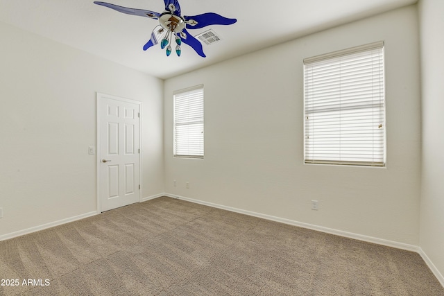 unfurnished room featuring carpet floors, visible vents, baseboards, and a ceiling fan