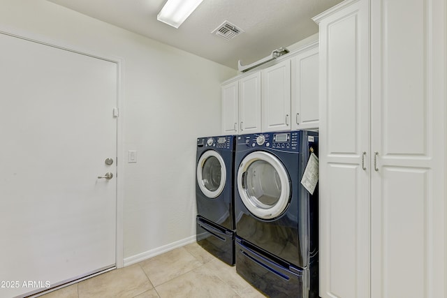 laundry area featuring light tile patterned flooring, separate washer and dryer, visible vents, baseboards, and cabinet space