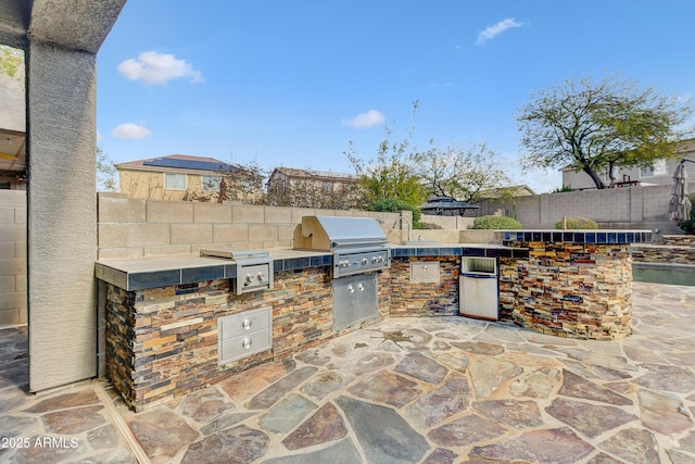 view of patio featuring exterior kitchen, a fenced backyard, and area for grilling