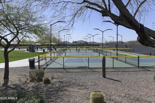 view of property's community with a tennis court and fence