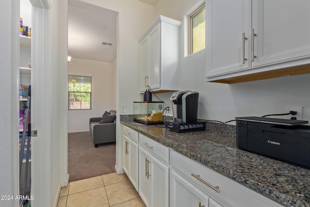 kitchen featuring dark stone countertops, light colored carpet, and white cabinets