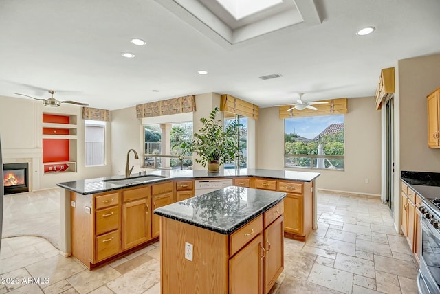 kitchen featuring gas stove, sink, a center island with sink, and ceiling fan