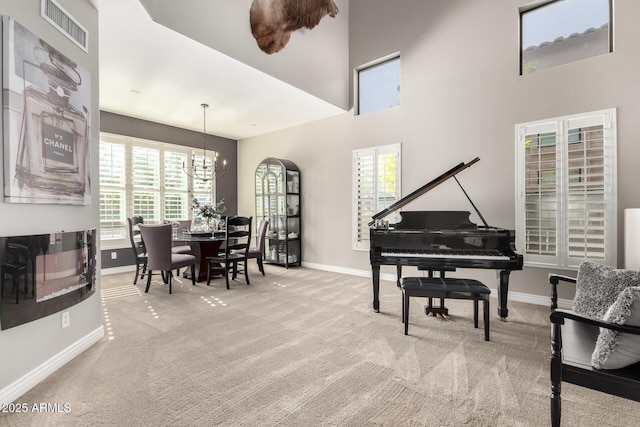 sitting room with a towering ceiling, light colored carpet, and a notable chandelier