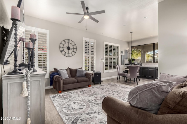 living room with ceiling fan with notable chandelier and light hardwood / wood-style flooring