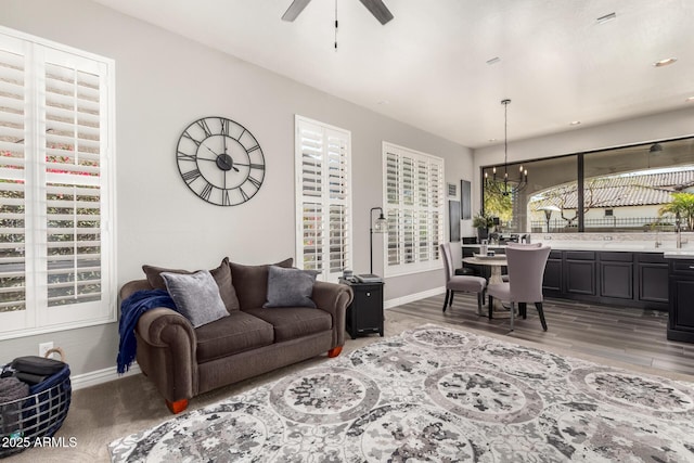 living room with hardwood / wood-style flooring and ceiling fan with notable chandelier