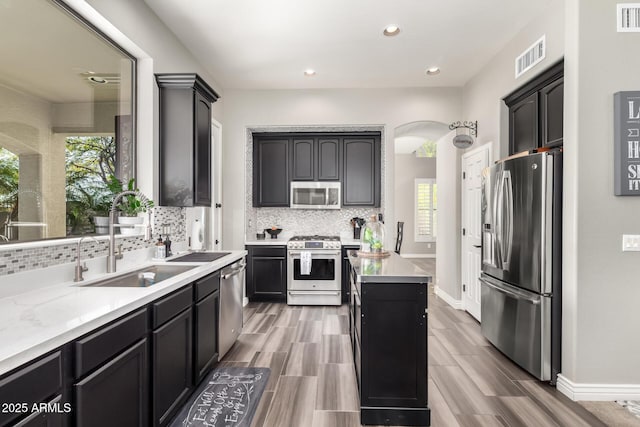 kitchen with sink, a kitchen island, a healthy amount of sunlight, and appliances with stainless steel finishes