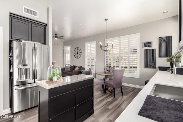 kitchen with pendant lighting, wood-type flooring, a center island, and stainless steel refrigerator with ice dispenser