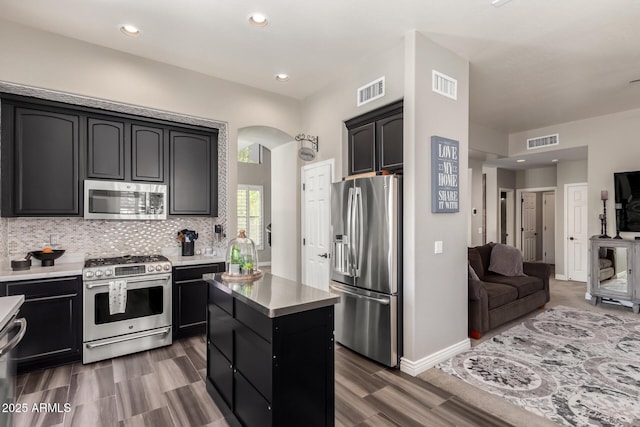 kitchen with tasteful backsplash, dark hardwood / wood-style floors, a center island, and appliances with stainless steel finishes