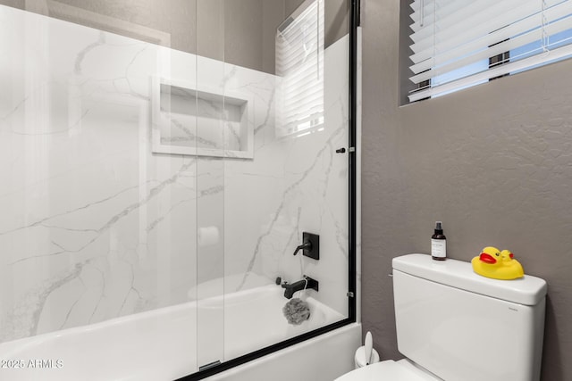 bathroom featuring toilet and combined bath / shower with glass door