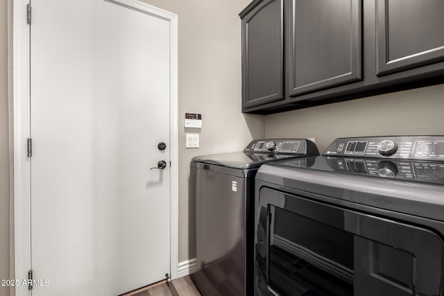 washroom with washer and clothes dryer, cabinets, and wood-type flooring