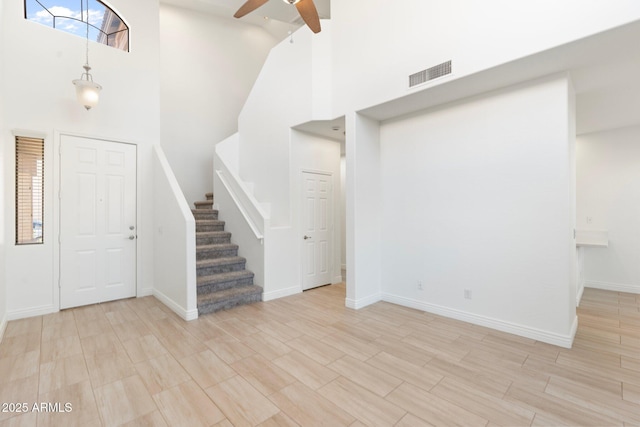 foyer entrance featuring ceiling fan and a towering ceiling