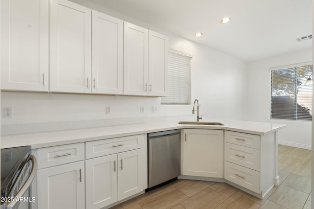 kitchen featuring sink, white cabinets, appliances with stainless steel finishes, and kitchen peninsula