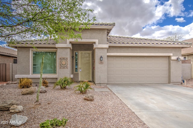 view of front of home with a tiled roof, stucco siding, driveway, and a garage