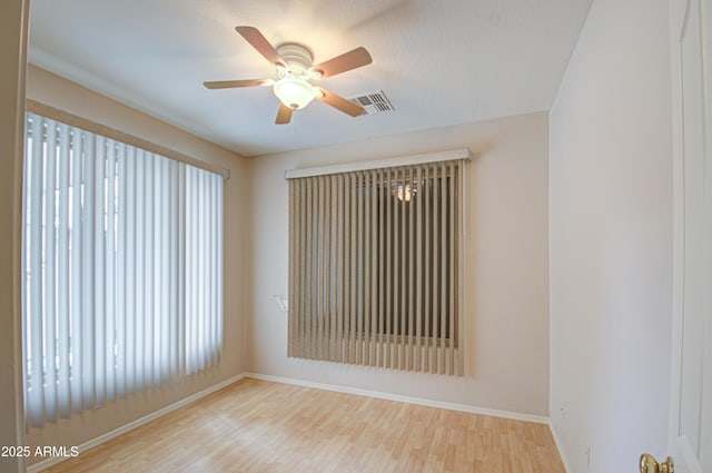 empty room with visible vents, plenty of natural light, ceiling fan, and wood finished floors