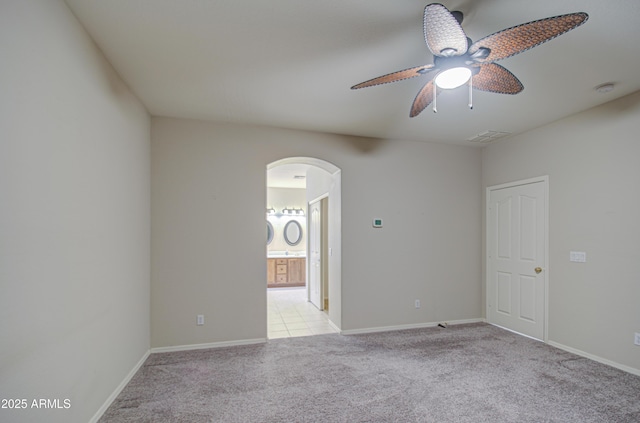 unfurnished room featuring visible vents, ceiling fan, baseboards, light carpet, and arched walkways