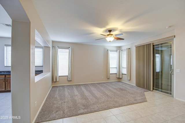 spare room featuring visible vents, plenty of natural light, light colored carpet, and ceiling fan