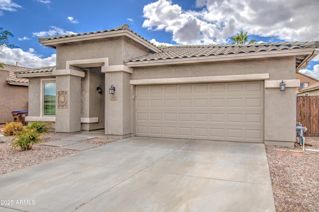 view of front facade featuring fence, a tiled roof, stucco siding, a garage, and driveway