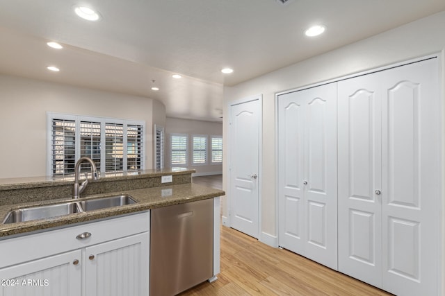 kitchen featuring light hardwood / wood-style floors, stainless steel dishwasher, sink, white cabinets, and dark stone counters